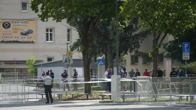 epa11342303 Police officers and onlookers stand near the cordoned-off crime scene where Slovak Prime Minister Robert Fico was shot earlier in the day, in Handlova, Slovakia, 15 May 2024. According to a statement from the Slovak government office on 15 May, "following a government meeting in Handlova, there was an assassination attempt on the Prime Minister of the Slovak Republic Robert Fico. He is currently being transported by helicopter to Banska Bystrica Hospital in a life-threatening condition." EPA/JAKUB GAVLAK