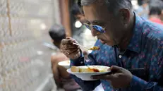 epa11198635 A commuter eats lunch at a street food shop in Kolkata, Eastern India, 04 March 2024. Kolkata is famous for its vibrant street food culture and Kathi Rolls, Puchkas (Pani Puris), Chop (Cutlets) Ghugni savoury snack made with dried white peas are some very famous dishes. EPA/PIYAL ADHIKARY