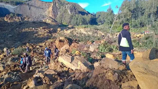 epa11365145 People walk with their belongings in the area where a landslide hit the village of Kaokalam, Enga province, Papua New Guinea, 24 May 2024. A landslide reportedly killed about 100 people in a remote village of northern Papua New Guinea. EPA/NINGA ROLE BEST QUALITY AVAILABLE AUSTRALIA AND NEW ZEALAND OUT EDITORIAL USE ONLY EDITORIAL USE ONLY