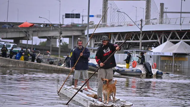 epa11346447 Two men use a boat made of roof tiles to navigate in a flooded area in the municipality of Canoas, Rio Grande do Sul state, Brazil, 16 May 2024. On 16 May, Brazilian rescue forces rescued several people with hypothermia who were still sheltering in their homes, amid the floods that have kept a large part of the city of Porto Alegre under water for almost two weeks. The municipality of Canoas, one of the most affected by the unprecedented flooding of the GuaÃba River, has nearly 70,000 houses surrounded and flooded by water. EPA/Andre Borges