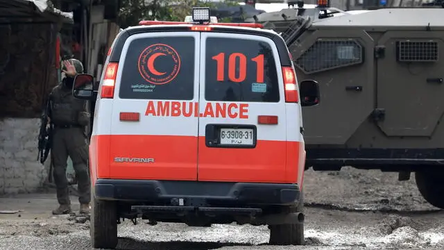 epa11085056 An Israeli soldier stops a Palestine Red Crescent Society ambulance as they block access to a road during an Israeli raid in the West Bank city of Tulkarem and its camp, 17 January 2024. At least four Palestinians were killed after Israeli forces stormed the city of Tulkarm and its camp on 17 January, according to the Palestinian Ministry of Health. EPA/ALAA BADARNEH