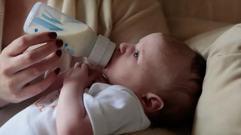 Un bambino beve il latte dal biberon