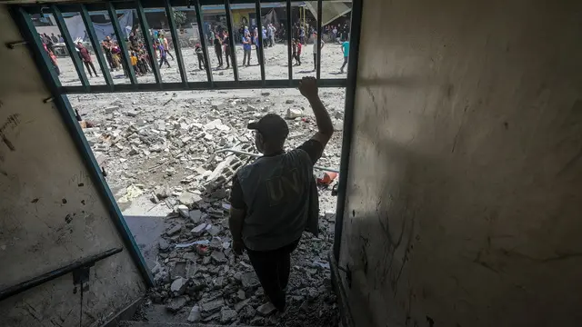 epa11392933 A UN employee inspects the destroyed UNRWA school following an Israeli air strike in Al Nusairat refugee camp in the central Gaza Strip, 06 June 2024. According to the Palestinian News Agency Wafa, at least 32 people were killed and dozens others were injured on early 06 June following an Israeli strike on a UNRWA school sheltering displaced Palestinians, located in the Nuseirat refugee camp in the central Gaza strip. The Israeli army said that it had "conducted a precise strike on a Hamas compound", whose members were " embedded in the UNRWA school". More than 36,000 Palestinians and over 1,400 Israelis have been killed, according to the Palestinian Health Ministry and the Israel Defense Forces (IDF), since Hamas militants launched an attack against Israel from the Gaza Strip on 07 October 2023, and the Israeli operations in Gaza and the West Bank which followed it. EPA/MOHAMMED SABER