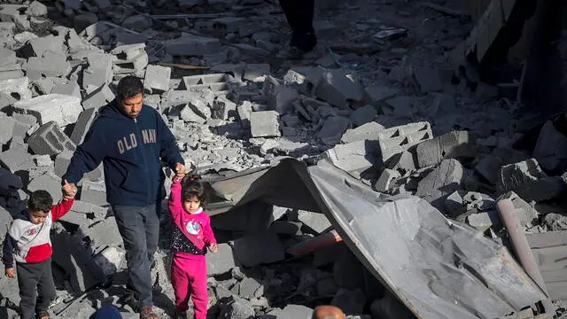epa11198392 A Palestinian man with two children walks among the rubble of a destroyed house following Israeli air strikes in Al Nusairat refugee camp, Gaza Strip, 04 March 2024. More than 30,500 Palestinians and over 1,300 Israelis have been killed, according to the Palestinian Health Ministry and the Israel Defense Forces (IDF), since Hamas militants launched an attack against Israel from the Gaza Strip on 07 October 2023, and the Israeli operations in Gaza and the West Bank which followed it. EPA/MOHAMMED SABER