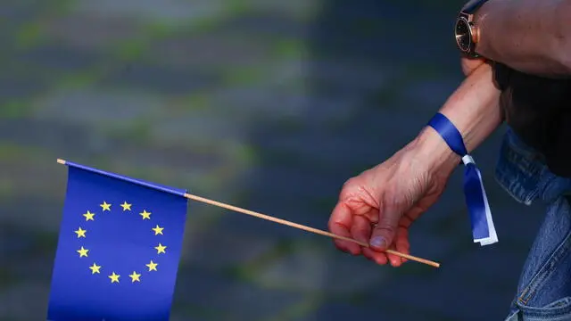 epa11373989 A spectator who follows a speech by French President Emmanuel Macron (not pictured) on the occasion of the European Festival, holds a European flag, on Neumarkt square in Dresden, Germany, 27 May 2024. Macron visits Germany from 26 to 28 May. The French President and Federal President Steinmeier will visit several regions of Germany together. It is the first state visit - the highest form of visit in diplomatic protocol - by a French president to Germany in 24 years. EPA/FILIP SINGER