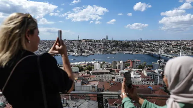 epa10854438 Tourists take pictures as they enjoy the view from the Galata Tower backdropped by the Suleymaniye Mosque in Istanbul, Turkey, 11 September 2023. EPA/ERDEM SAHIN
