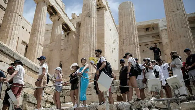 epa11403675 A visitor uses a handheld fan as tourists line up to exit the Acropolis during a heatwave, in Athens, Greece, 11 June 2024. The extended high pressure area over the coasts of Africa and central Mediterranean, which is accompanied by very warm air masses, is gradually extending eastward and will bring very high temperatures in Greece from 11 until 14 June. A circular of the Interior Ministry outlines how civil services will operate during the heatwave forecast in Greece by the National Meteorological Service. EPA/KOSTAS TSIRONIS