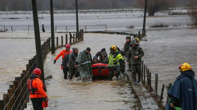 epa11404891 Carabineros and emergency personnel evacuate people who were isolated due to the overflowing of the Pichilo River, as a result of heavy rains in the Los Guzmanes sector, in the commune of Arauco, Bio Bio region, Chile, 11 June 2024. EPA/Ignacio Vasquez