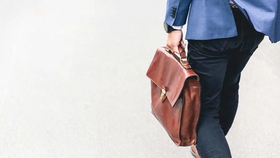Un uomo esce dall'ufficio con la valigetta (foto Unsplash)