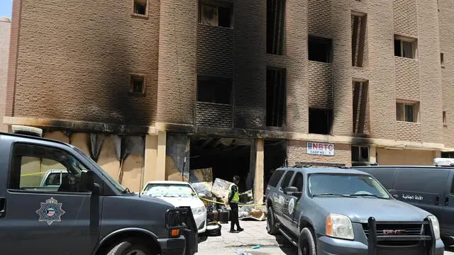 epa11405262 A Kuwaiti policeman stands in front of a residential building after a fire broke out in Mangaf area, southern Ahmadi governorate, Kuwait, 12 June 2024. According to the Ministry of Interior, at least 35 people were killed and dozens injured after a fire broke out at a building housing workers. The fire had been contained and an investigation into the cause of fire was launched, the ministry added giving no further information about the nationality of the causalities. EPA/NOUFAL IBRAHIM