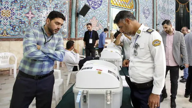 epa11330946 An Iranian traffic police officer (R) casts his electronic vote during the second round of parliamentary elections in Tehran, Iran, 10 May 2024. Iranians on 10 May vote for the remaining seats in Iran's parliament in the second round of the country's parliamentary elections. The first round was held on 01 March 2024. EPA/ABEDIN TAHERKENAREH