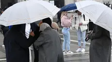 Persone camminano in piazza Duomo indosssando giacche invernali e proteggendosi dalla pioggia con ombrelli, Milano, 22 febbraio 2024. Sono in arrivo 5 giorni di maltempo, con piogge e vento forte. Previste anche abbondanti nevicate sulle Alpi dove cadrà oltre un metro di neve. ANSA/DANILE DAL ZENNARO