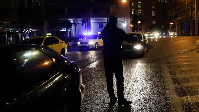 epa08771816 Police officers stand at a checkpoint to make sure people follow coronavirus restrictions, at Syntagma square in Athens, Greece, 25 october 2020. The measures, announced on 22 October during a televised address to the nation by Prime Minister Kyriakos Mitsotakis, saw overnight curfews coming into effect on 24 October in the country's high alert areas, from 00:30 am to 05:00 am, while wearing face masks will now become mandatory everywhere, both indoors and outdoors and in all public services and private companies. EPA/ORESTIS PANAGIOTOU