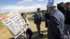 Il proprietario della discarica di Malagrotta, Manlio Cerroni, nell'area di Monti dell'Ortaccio, di fronte a lui una manifestante mostra un cartello contro la discarica, 29 ottobre 2012. ANSA/ MASSIMO PERCOSSI