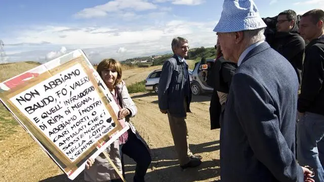 Il proprietario della discarica di Malagrotta, Manlio Cerroni, nell'area di Monti dell'Ortaccio, di fronte a lui una manifestante mostra un cartello contro la discarica, 29 ottobre 2012. ANSA/ MASSIMO PERCOSSI
