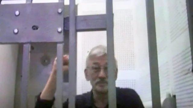 epa11472037 Jailed human rights activist Oleg Orlov is seen on TV screen as he participates in a court appeal hearing via video link from his prison against his sentence at the Moscow City Court in Moscow, Russia, 11 July 2024. The Golovinsky Court of Moscow sentenced Oleg Orlov, co-chair of the Memorial human rights center (liquidated by a Supreme Court ruling), to two and a half years in prison on February 27, 2024, for "repeatedly discrediting the Russian army. EPA/MAXIM SHIPENKOV