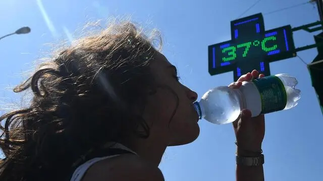 Una ragazza beve dell'acqua mentre il termometro segna i 37 gradi - Foto Ansa © www.giornaledibrescia.it
