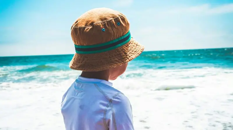 Un bambino con il cappello davanti al mare