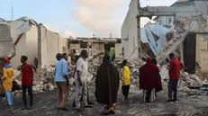 epa11479472 People look at the damage at the site of a bomb attack in Mogadishu, Somalia, 15 July, 2024. Nine people were killed and more than 20 wounded late 14 July when a car bomb struck a cafe packed with football fans watching the final of the Euro 2024, Mohamed Yusuf, an official from the national security agency confirmed on 15 July. EPA/SAID YUSUF WARSAME