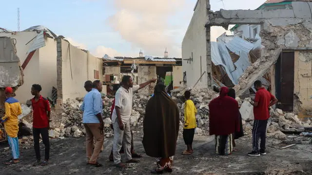 epa11479472 People look at the damage at the site of a bomb attack in Mogadishu, Somalia, 15 July, 2024. Nine people were killed and more than 20 wounded late 14 July when a car bomb struck a cafe packed with football fans watching the final of the Euro 2024, Mohamed Yusuf, an official from the national security agency confirmed on 15 July. EPA/SAID YUSUF WARSAME