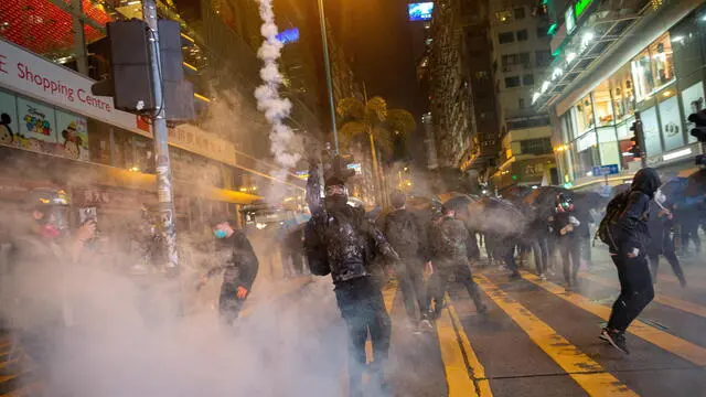 epa08089185 Pro-democracy protesters react after riot police shot tear gas during a rally in Tsim Sha Tsui, Hong Kong, China, 24 December 2019. Police fired multiple rounds of tear gas in the tourist district of Tsim Sha Tsui on Christmas eve, after clashes broke out inside a shopping mall as a large number of protesters join a 'Christmas shopping' rally. Hong Kong has entered its seventh month of mass protests, which were originally triggered by a now withdrawn extradition bill, and have since turned into a wider pro-democracy movement. EPA/JEROME FAVRE