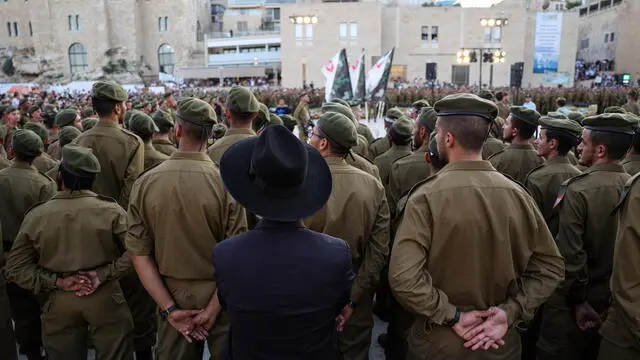 epa11471293 An Ultra-Orthodox Jewish man stands near Israeli soldiers from the Netzah Yehuda Battalion during a swearing-in ceremony at the end of their military training, when graduates receive an assault rifle and a Bible (Tanakh), at the Western Wall in the Old City of Jerusalem, 10 July 2024. The Netzah Yehuda Battalion is an infantry battalion of the Israel Defense Forces (IDF), created to accommodate ultra-Orthodox Jews fighters. Israeli Defense Minister Yoav Galant announced on 09 July, that the IDF will begin the process of drafting ultra-Orthodox men in August 2024. The move comes after Israel's Supreme Court ruled that ultra-Orthodox Jewish men must be drafted into military service, a decision that endangers the stability of Netanyahu's coalition government. EPA/ABIR SULTAN