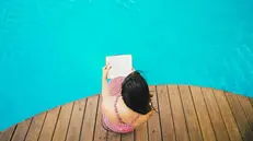 Una ragazza legge a bordo piscina