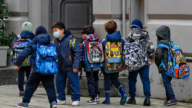 Bambini e genitori all'ingresso della scuola elementare ' De Amicis' di Napoli dove solo le classi di prima e seconda sono tornate in aula dopo settimane di stop dovuto alla pandemia da Covid-19 a Napoli, 11 gennaio 2020 ANSA/CIRO FUSCO
