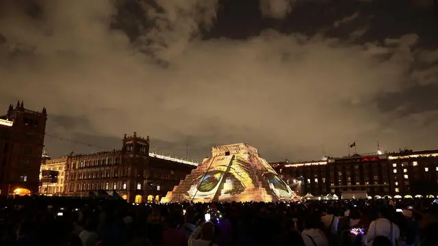 epa11476980 People watch the 'El Pueblo Maya and Felipe Carrillo Puerto. Memoria luminosa II' light show, projected onto a representation of the pyramid of Kukulcan, in the Zocalo plaza of Mexico City, Mexico, 13 July 2024. EPA/Jose Mendez