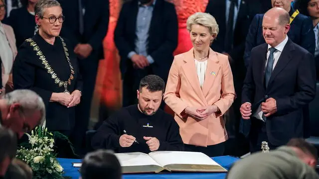 epaselect epa10627893 Ukrainian President Volodymyr Zelensky (C) signs the golden book of Aachen beside the Mayor Sibylle Keupen (L), European Commission President Ursula von der Leyen (2-R) and German Chancellor Olaf Scholz (R) after receiving the Charlemagne Prize (Karlspreis) during the award ceremony in the town hall of Aachen, Germany, 14 May 2023. This year's prize is awarded to Ukraine's President Volodymyr Zelensky and the Ukrainian people. The International Charlemagne Prize of Aachen has been awarded annually since 1950 to people who have contributed to the ideals upon which Europe has been founded. EPA/FRIEDEMANN VOGEL / POOL