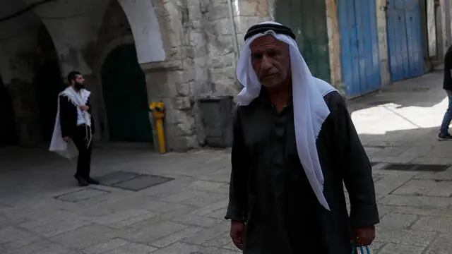 epa10655221 A Palestinian man (R) and an Ultra-Orthodox Jew (L) pass the Cotton Gate market in Jerusalem’s old city leading to the Al-Aqsa complex, or the 'Temple Mount' during the Jewish holiday of Shavuot, commonly known as the 'Feast of Weeks', in Jerusalem, 26 May 2023. Shavuot is a major Jewish holiday that occurs on the sixth day of month of Sivan in the Hebrew calendar. EPA/ATEF SAFADI