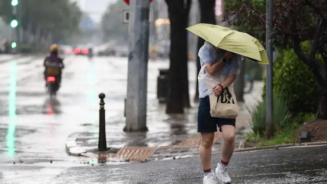 epa11493856 A woman walks with an umbrella during heavy rain, on a street in Beijing, China, 24 July 2024. The Beijing Municipal Bureau of Meteorology issued an orange rainstorm alert on 24 July 2024. Beijing is expected to experience heavy rainfall, while rainfall may exceed 150 millimeters in 24 hours in the outer districts of Miyun, Huairou, Pinggu and Shunyi. The northwest mountainous areas and eastern regions of the capital city may receive rainfall in excess of 100-150 millimeters within 24 hours. EPA/WU HAO