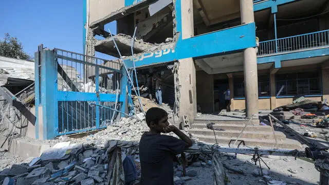 epa11478335 A Palestinian boy stands near the rubble of a damaged UNRWA school following an Israeli air strike in Al Nuseirat refugee camp, central Gaza Strip, 14 July 2024. At least 12 people were killed following an Israeli air strike in the camp, according to the Palestinian Ministry of Health. The Israeli military stated on 14 July, that the Israeli Air Force (IAF) struck the area of UNRWA's Abu Oraiban School School building in Nuseirat, claiming that the location served as a 'hideout and operational infrastructure' to direct and carry attacks against Israeli troops operating in the Gaza Strip. More than 38,000 Palestinians and over 1,400 Israelis have been killed, according to the Palestinian Health Ministry and the Israel Defense Forces (IDF), since Hamas militants launched an attack against Israel from the Gaza Strip on 07 October 2023, and the Israeli operations in Gaza and the West Bank which followed it. EPA/MOHAMMED SABER