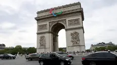 epa11496584 Cars pass in front of the Arc de Triomphe which is decorated with the colors of the Paralympic Games ahead of the opening ceremony of the Paris 2024 Olympic Games, in Paris, France, 25 July 2024. The opening ceremony of the Paris 2024 Olympic Games will begin on 26 July with a nautical parade on the Seine river and end on the protocol stage in front of the Eiffel Tower. EPA/ALI HAIDER