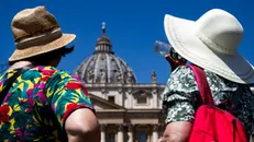 Turisti si riparano dal caldo in piazza San Pietro, Roma, 30 giugno 2024. ANSA/ANGELO CARCONI