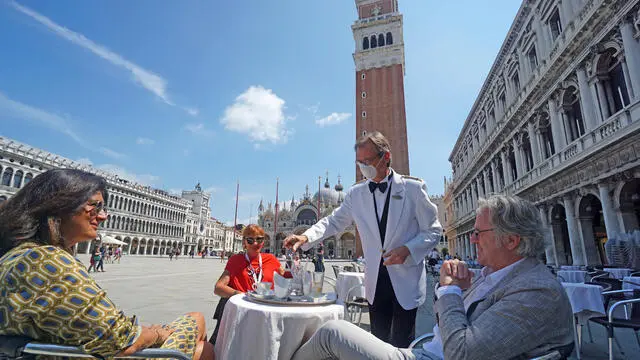 Un cameriere serve alcuni clienti seduti all’esterno dello storico Caffè Florian, in piazza San Marco, oggi 12 giugno 2020. ANSA/ANDREA MEROLA