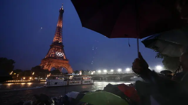 epa11497977 People watching boats with athletes passing by the Eiffel Tower during the Opening Ceremony of the Paris 2024 Olympic Games, in Paris, France, 26 July 2024. EPA/ANNA SZILAGYI