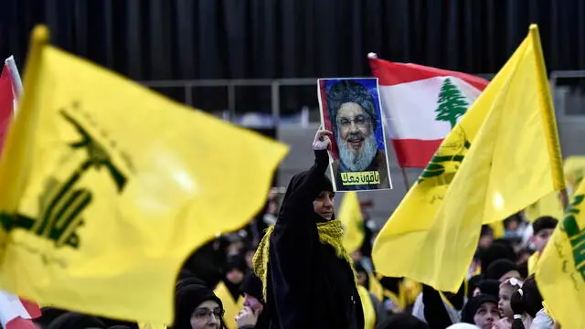 epa11260776 Hezbollah supporters carry flags of their party and a picture of Hezbollah leader Hassan Nasrallah as they listen to his speech during a gathering to commemorate Al Quds Day (Jerusalem Day) in a suburb of Beirut, Lebanon, 05 April 2024. Al Quds Day was declared in 1979 by the late Ayatollah Khomeini, founder of the Islamic Iranian Republic, who called on the world's Muslims to show solidarity with Palestinians on the last Friday of the fasting month of Ramadan. EPA/WAEL HAMZEH