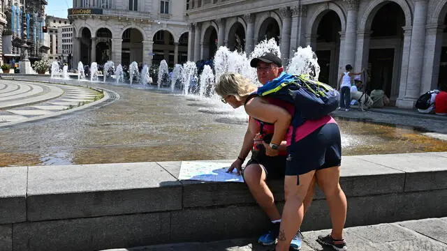 Turisti in giro per la citta' nonostante il grande caldo di questi giorni. Alcuni cercano refrigerio nelle fontane di piazza De Ferrari. Genova, 17 luglio 2024. ANSA/LUCA ZENNARO