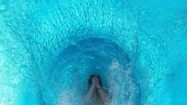 epa04827978 A youth jumps into a swimming pool and creates a whirlpool effect l in Cologne, Germany, 02 July 2015. The summer is hitting above 30 degrees in several cities across Europe. EPA/MAJA HITIJ