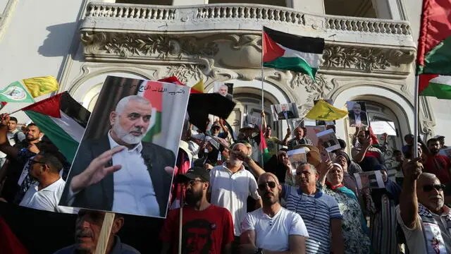 epa11513582 Protesters carry pictures of Hamas leader Ismail Haniyeh, who was killed in Iran, and Palestinian flags during a protest to condemn his killing, organized by the Popular Current, in Tunis, Tunisia, 31 July 2024. According to an Iranian Revolutionary Guard Corps (IRGC) statement on 31 July, Haniyeh and one of his bodyguards were targeted and killed in Tehran on 31 July 2024. EPA/MOHAMED MESSARA