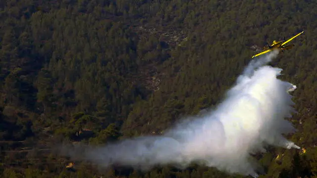 epa11511284 A firefighting plane drops water to cool the perimeter area of the Benasau forest fire in Alicante, Spain, 31 July 2024. Hundreds of people have been evacuated and roads have been cut off as a result of the fire. EPA/MORELL