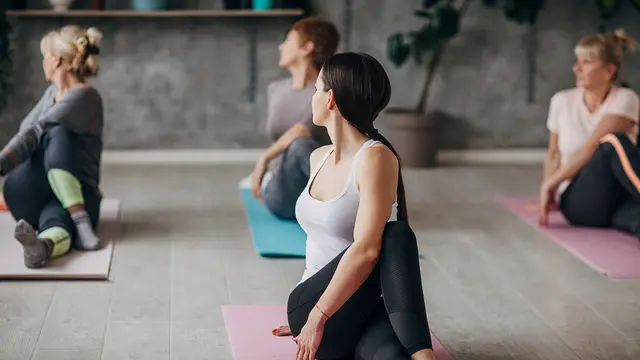 Four women, female yoga instructor and three senior women exercising together in yoga studio.