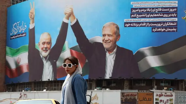 epa11515091 A woman walks past a billboard depicting Iranian President Massed Pezeshkian (R) and Hamas late political leader Ismail Haniyeh, at Valiasr Square in Tehran, Iran, 01 August 2024. Haniyeh and one of his bodyguards were targeted and killed in Tehran on 31 July 2024, the Iranian Revolutionary Guard Corps (IRGC) confirmed. EPA/ABEDIN TAHERKENAREH