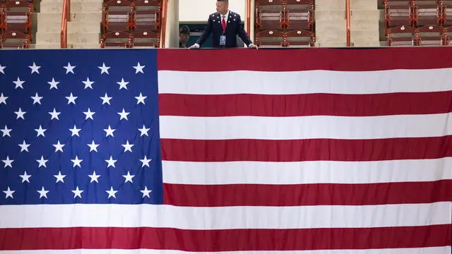 epa11513991 Volunteer Jack Robertson stands over the US national flag at a Trump rally at New Holland Arena in Harrisburg, Pennsylvania, USA, 31 July 2024. This is the first Trump rally in Pennsylvania since the assassination attempt that resulted in Trump's injury during a rally on 13 July. EPA/MICHAEL REYNOLDS