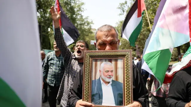 epa11510974 Iranians carry the portrait of late Hamas political leader Ismail Haniyeh and wave Palestinian flags during a protest at Tehran University in Tehran, Iran, 31 July 2024. According to an Iranian Revolutionary Guard Corps (IRGC) statement on 31 July, Hamas political leader Ismail Haniyeh and one of his bodyguards were targeted and killed in Tehran on 31 July 2024. EPA/ABEDIN TAHERKENAREH