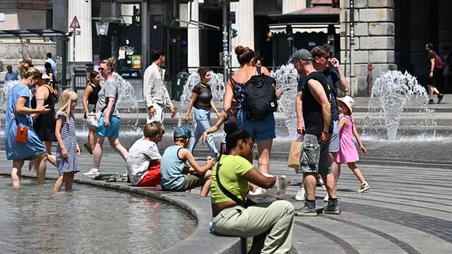 Turisti in giro per la citta' nonostante il grande caldo di questi giorni. Alcuni cercano refrigerio nelle fontane di piazza De Ferrari. Genova, 17 luglio 2024. ANSA/LUCA ZENNARO