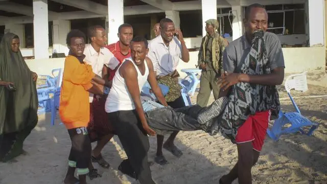 epa05117436 People carry an injured man after Somali security forces took control over of the restaurant and ended the siege where gunmen exploded car bombs and opened fire on people the night before, 22 January 2016. At least 20 people were killed in two suicide bombings targeting a popular beach hotel and a restaurant 21 January in the Somali capital Mogadishu, police and witnesses said. A car laden with explosives rammed into the Beach View Hotel on Lido beach, after which four suspected militants from Islamist group al-Shabaab opened fire at the hotel, police representative Ahmed Aloley said. EPA/SAID YUSUF WARSAME