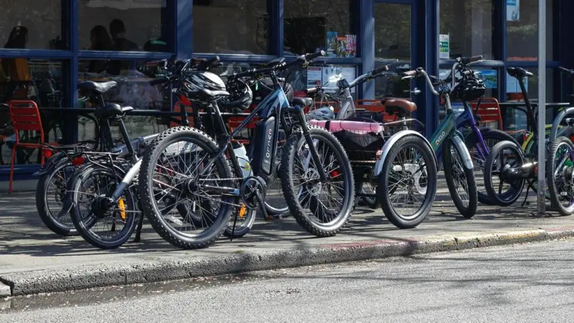 Nella foto d'archivio, bicilette elettriche parcheggiate in strada