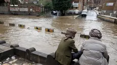 epa11553383 People sit near a flooded street following heavy rains in Sana'a, Yemen, 17 August 2024. Heavy rains and flash floods have hit large parts of Yemen over the past two weeks, leaving about 98 people killed and over 600 others injured, according to a statement by the United Nations. EPA/YAHYA ARHAB